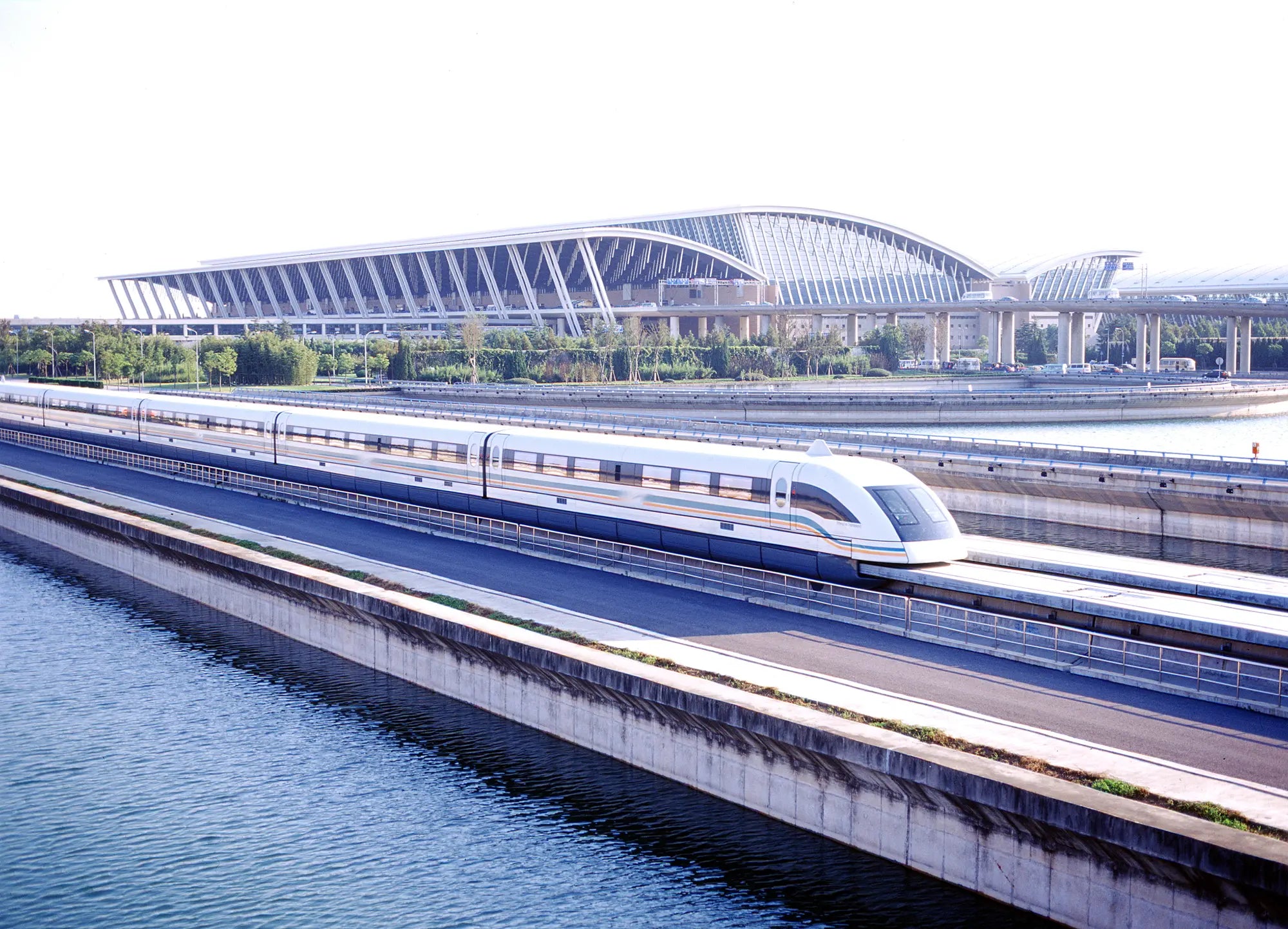 Shanghai Maglev train traveling at high speed over a clear river on an elevated track