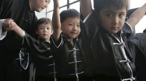 Kung Fu master guiding children to correct their martial arts posture during class in Shanghai.