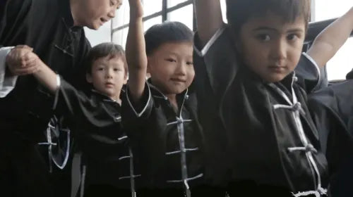 Kung Fu master guiding children to correct their martial arts posture during class in Shanghai.
