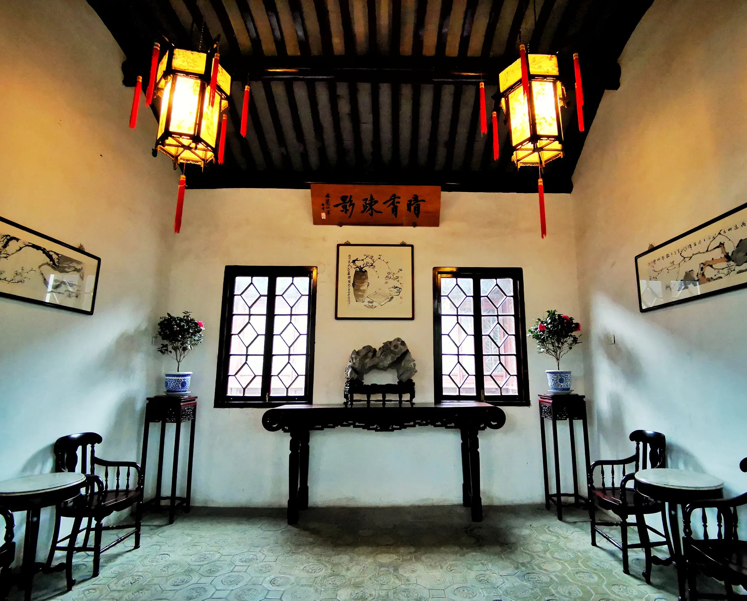 Traditional Chinese room in Lion Grove Garden with wooden table, red lanterns, calligraphy, and natural light filtering through lattice windows.