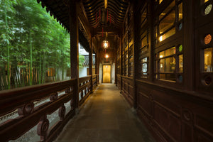 Covered wooden corridor with carved details and glowing lanterns, beside a swaying bamboo grove, in Lion Grove Garden, Suzhou.