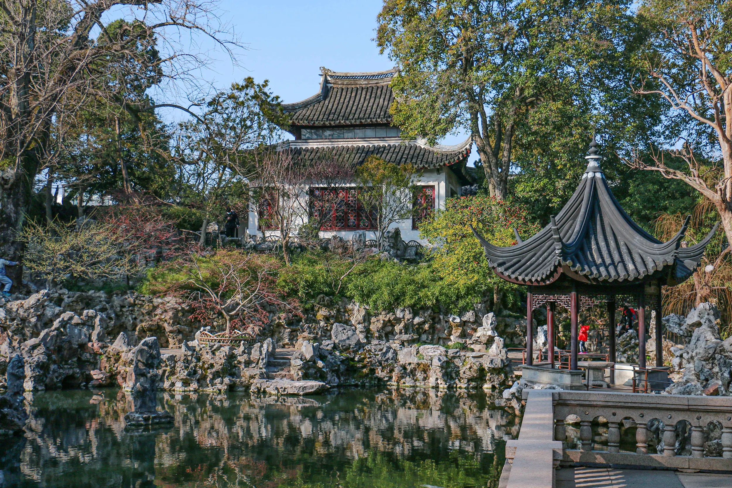 Traditional Chinese pavilion, rockeries, and reflections in the tranquil pond at Lion Grove Garden in Suzhou, China.