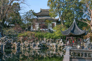 Traditional Chinese pavilion, rockeries, and reflections in the tranquil pond at Lion Grove Garden in Suzhou, China.