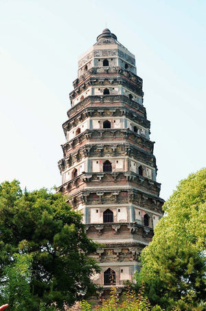 Upward close-up view of the leaning Tiger Hill Pagoda (Yunyan Pagoda) in Suzhou, surrounded by trees