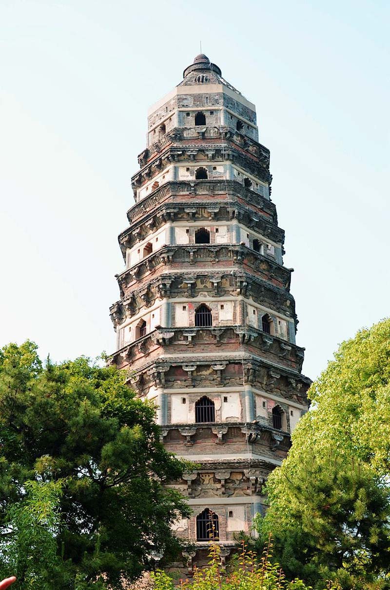 Upward close-up view of the leaning Tiger Hill Pagoda (Yunyan Pagoda) in Suzhou, surrounded by trees
