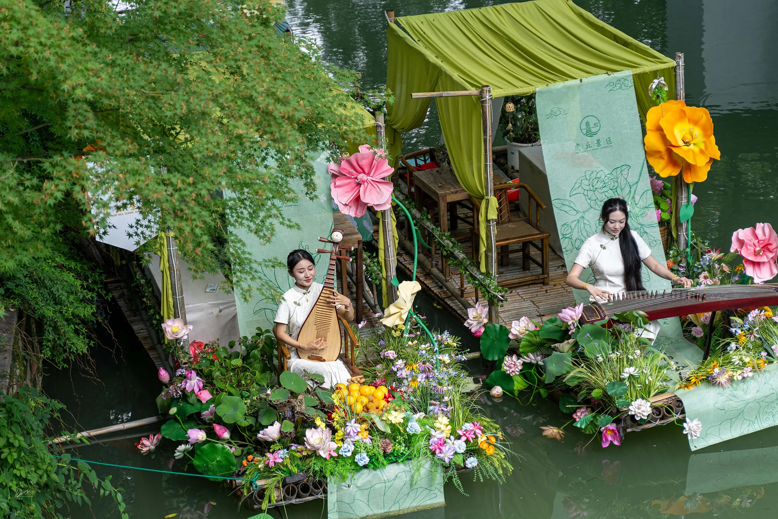 Two women performing traditional Chinese music by the riverside at Tiger Hill, one playing the guzheng and the other the pipa