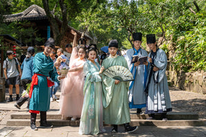 A group of Chinese men and women in traditional clothing posing for photos in Tiger Hill Scenic Area