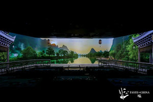 Dining table set with a wall projection of Chinese mountains, rivers, and pavilion, creating an immersive experience at The Bund, Shanghai.