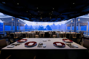 Immersive Chinese pavilion and landscape projected on a large screen, with neatly set dining table ready for guests at The Bund, Shanghai.