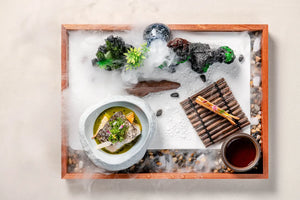 A fish dish served with tea, miniature rockery, and mist effects, creating an artistic presentation at The Bund, Shanghai.
