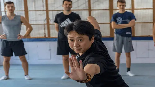 A middle-aged Chinese Kung Fu master demonstrating martial arts to a foreign student during a cultural class in Shanghai.