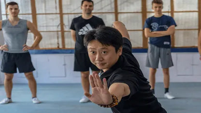 A middle-aged Chinese Kung Fu master demonstrating martial arts to a foreign student during a cultural class in Shanghai.