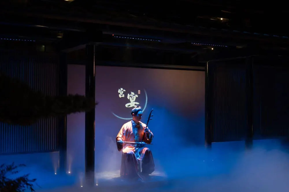 A man playing the erhu, a traditional Chinese two-stringed instrument, during a cultural performance.