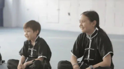 Two foreign children attentively listening to a Kung Fu lesson in Shanghai martial arts class.