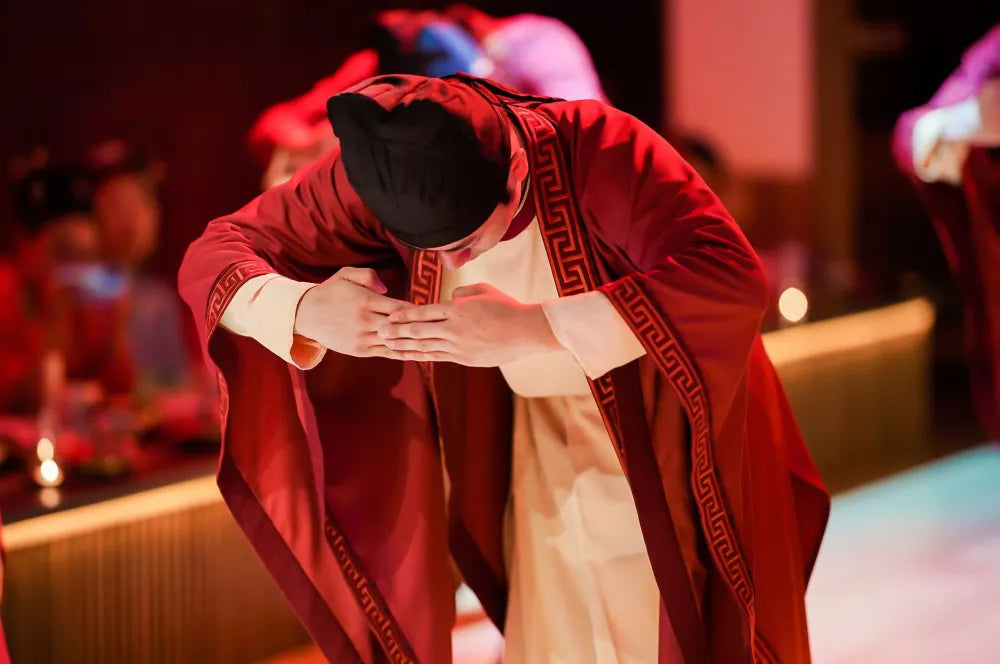 A man wearing traditional Tang suit performing a respectful bow during a cultural ceremony.