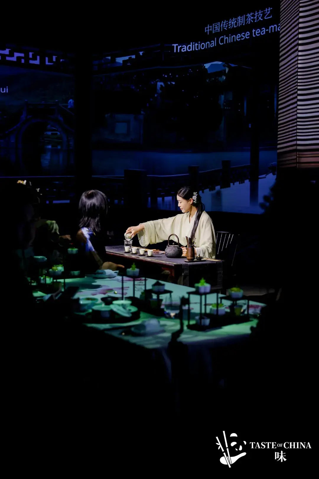 A lady demonstrating traditional Chinese tea ceremony, with guests seated to experience tea culture at The Bund, Shanghai.